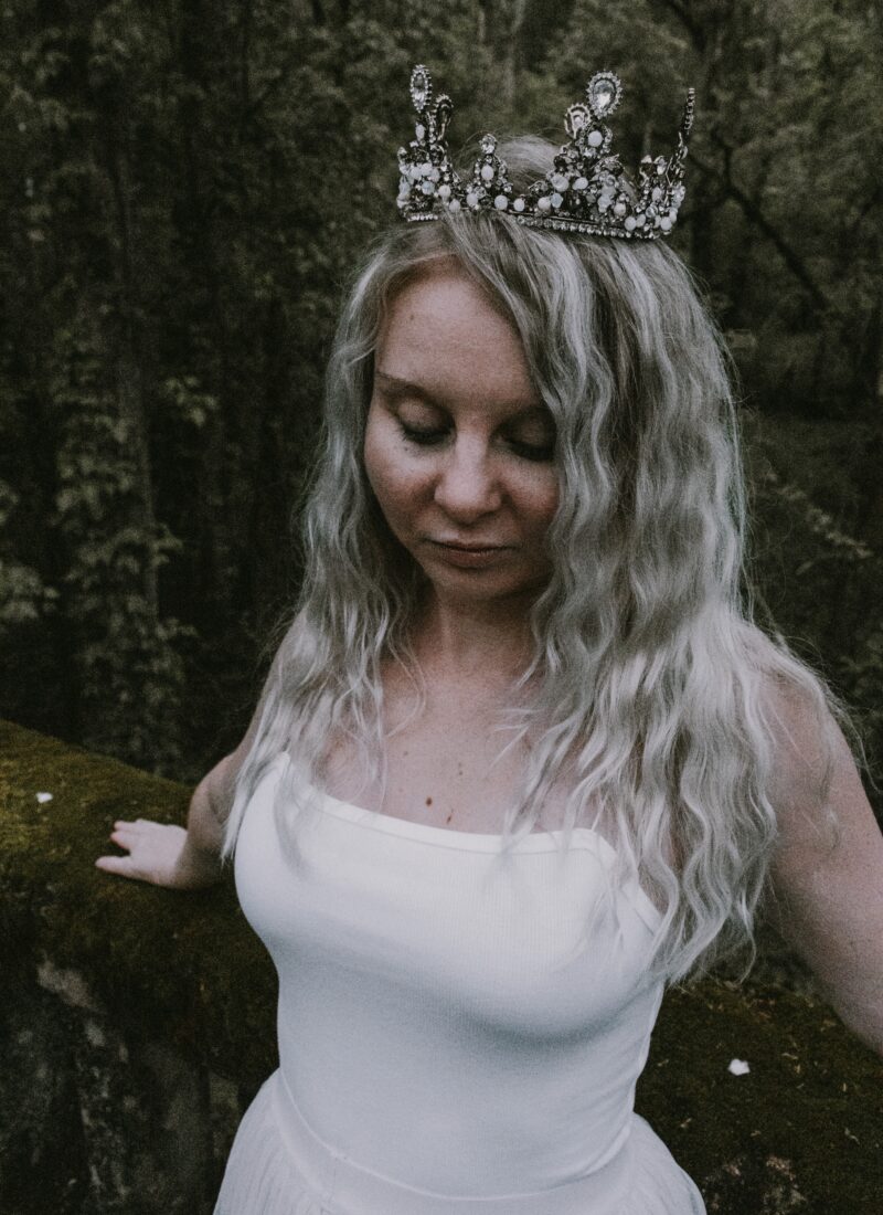 Photography of Stephanie in a crown, looking down, thinking about her DNA story.